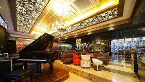 Un'ampia hall con un grande pianoforte a coda, comodi posti a sedere e un lampadario.