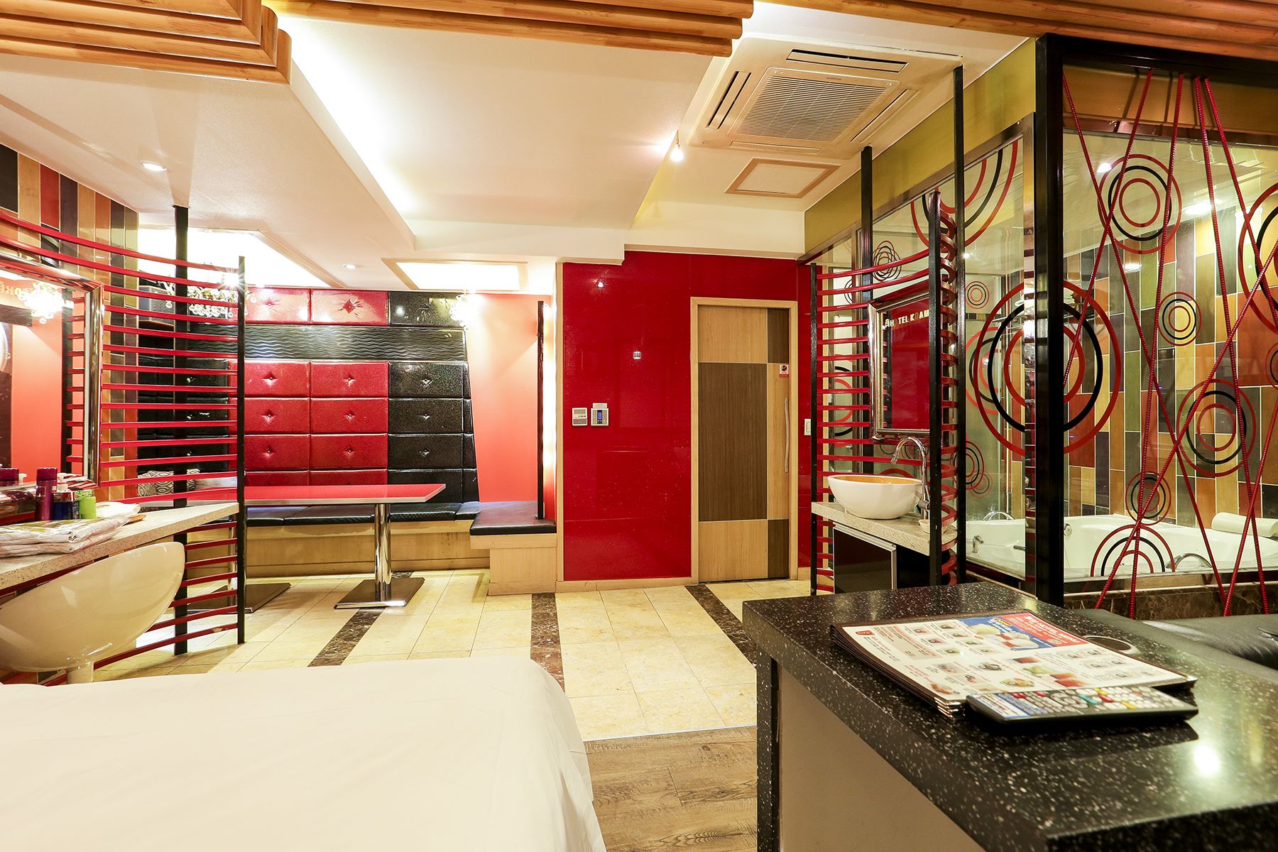 Een hotelkamer met een bed, een bureau, een kaptafel met spiegel en een rode wand.