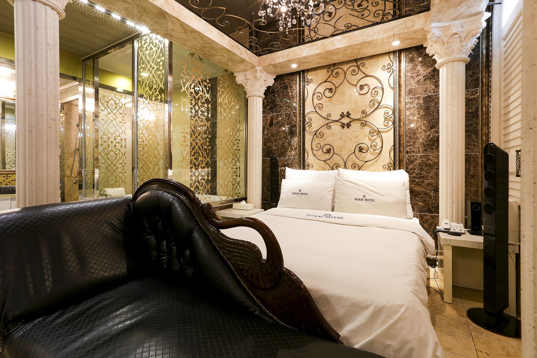 A luxurious hotel room with a large bed, a leather sofa, and a decorative headboard.