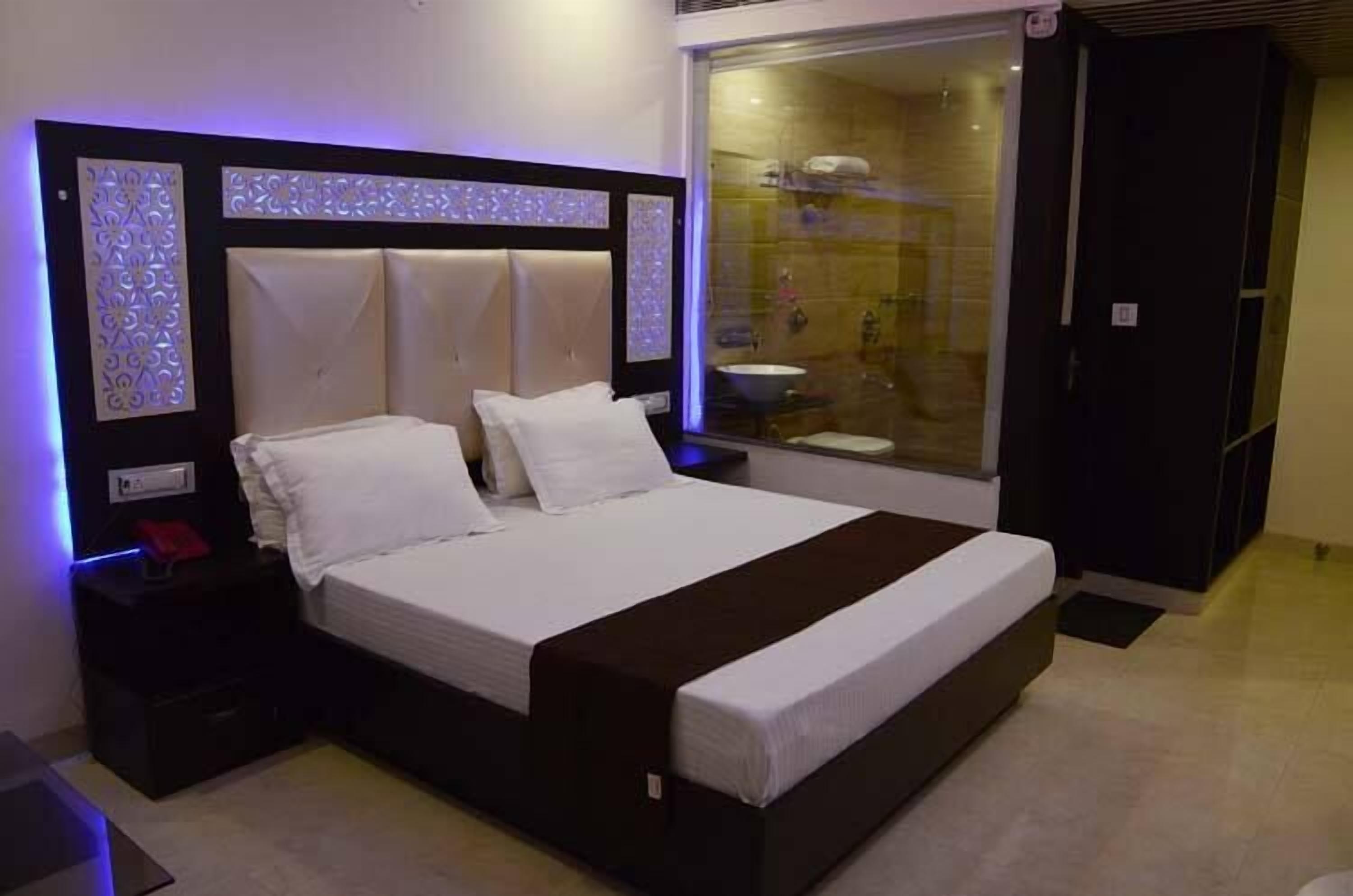 Una camera da letto moderna con un letto grande, un comodino, una tavola da notte, una finestra con vista sul bagno e una porta scorrevole.