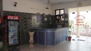 A reception area with a Coca-Cola refrigerator, a reception desk, and a sign for Hotel Surya Palace. - Hotel Surya Palace (Chandigarh)