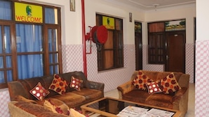 A room with two brown leather sofas, each with patterned cushions, a glass coffee table, and a 'WELCOME' sign above the door. - Hotel Surya Palace (Chandigarh)
