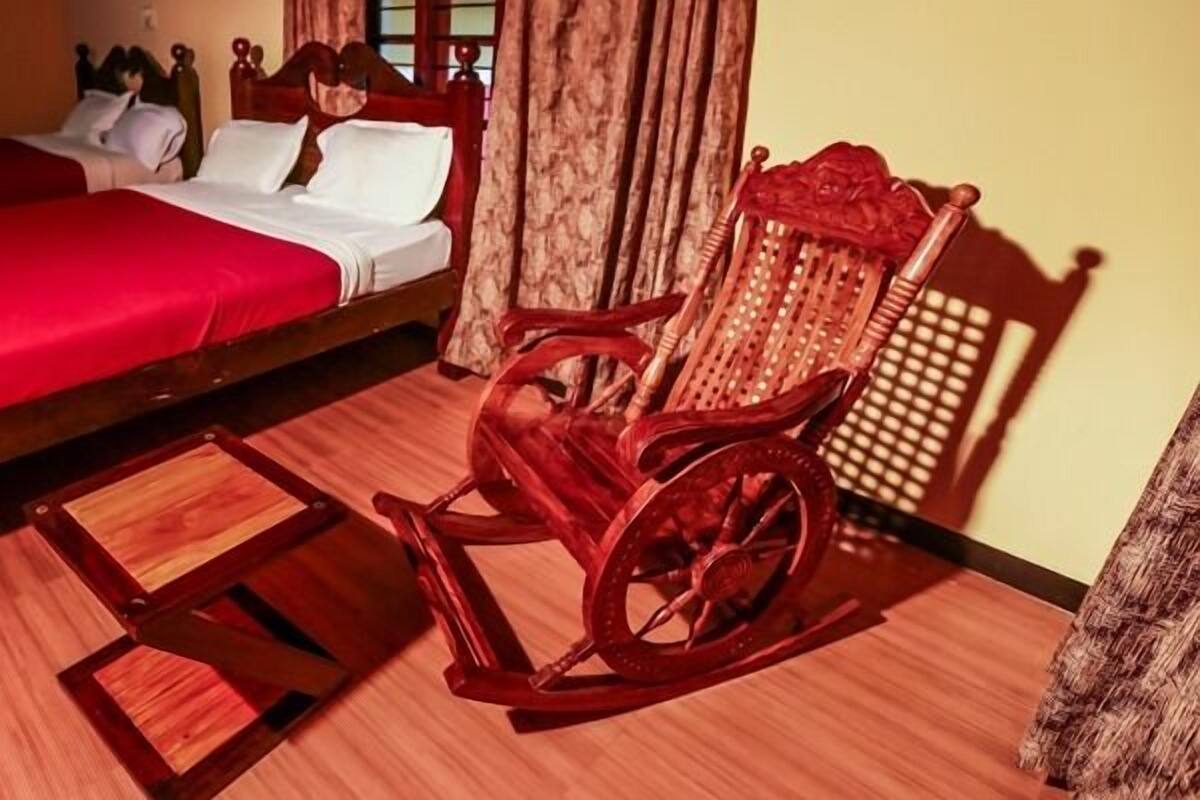 Una habitación con una cama grande, un sillón mecedora y una pequeña mesa de madera.