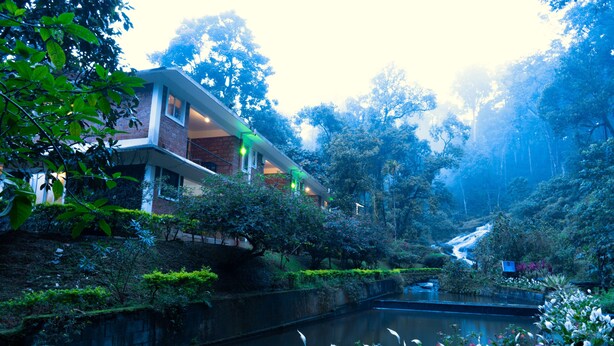 Una casa moderna con fachada de ladrillo, ventanas amplias y un balcón con vista al río.