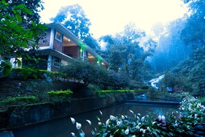 Una casa moderna con fachada de ladrillo, ventanas amplias y un balcón con vista al río.