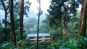 Un hotel ubicado en un bosque exuberante, con varios pisos y techo plano.