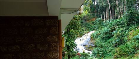 A balcony with a view of a lush garden and a waterfall.