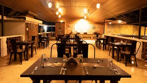 Un restaurante con techo de madera y paredes de ladrillo, que cuenta con varias mesas y sillas para comer.