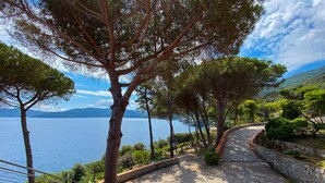 A terrace with a view of the sea, surrounded by trees and a stone wall. - Intur Residence (Marciana Marina)