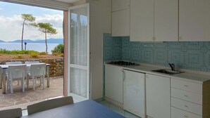 A kitchen with white cabinets, a gas stove, and a view of the sea. - Intur Residence (Marciana Marina)