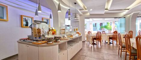 A modern dining area with a buffet counter, wooden chairs, and a view of the outdoors.