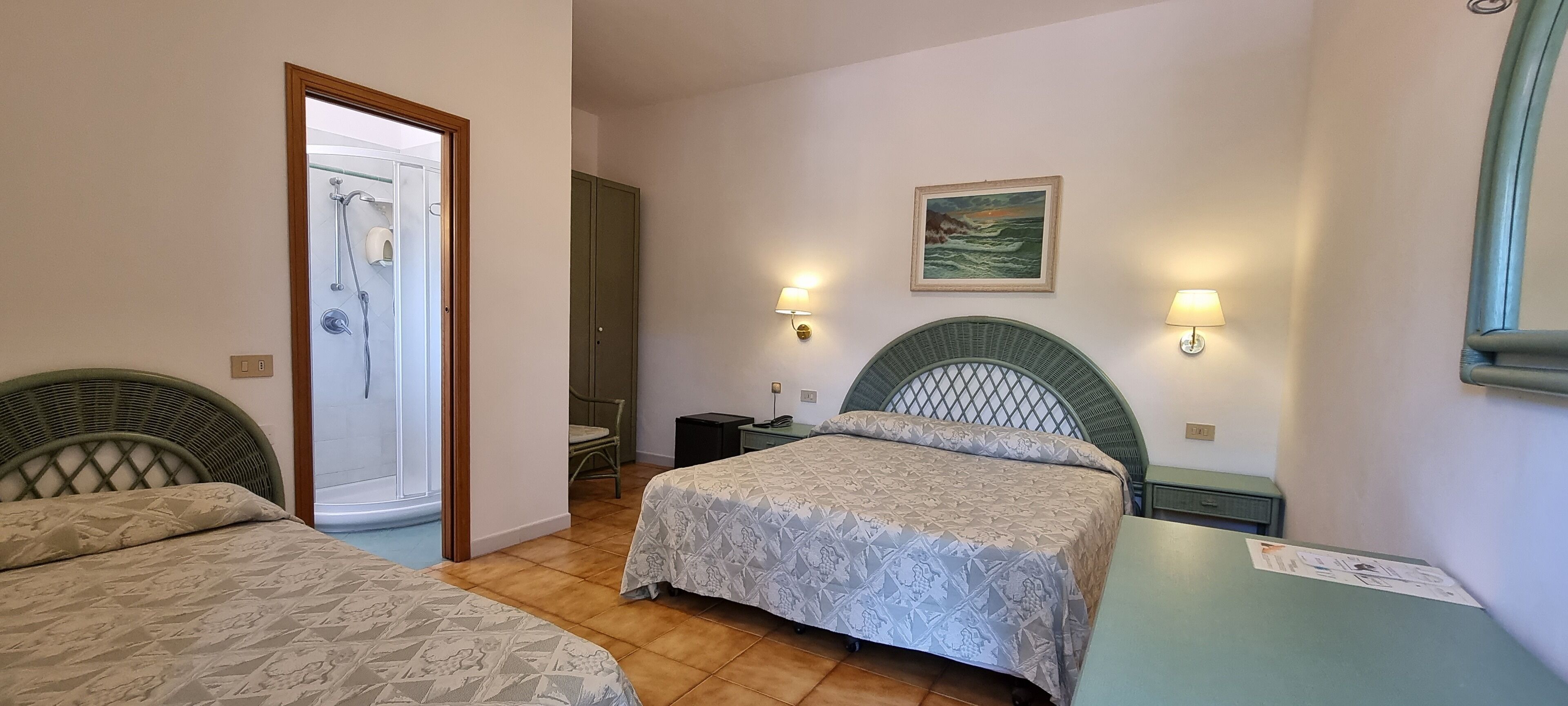A hotel room with two beds, a shower, a painting, and wall sconces.
