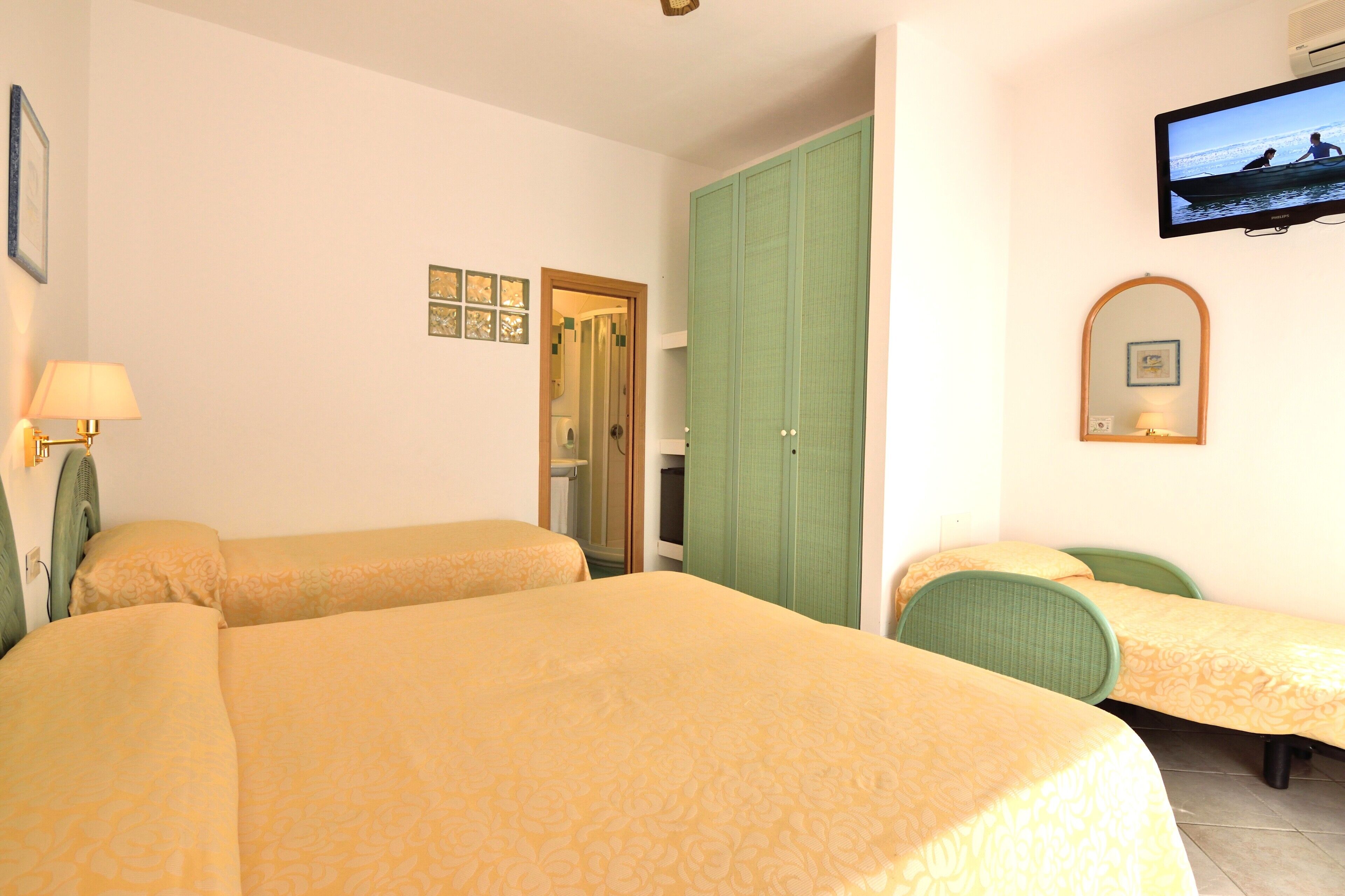 A hotel room with two beds, a television, a wardrobe, and a mirror.