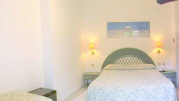 A bedroom with a bed, two bedside tables, a nightstand, a lamp, and a painting on the wall.