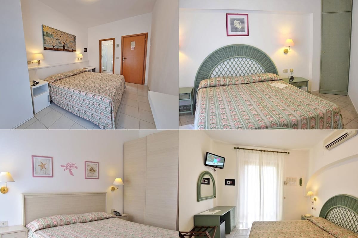 Ein Hotelzimmer mit Bett, Schreibtisch, Stuhl, Fernseher und Kleiderschrank.