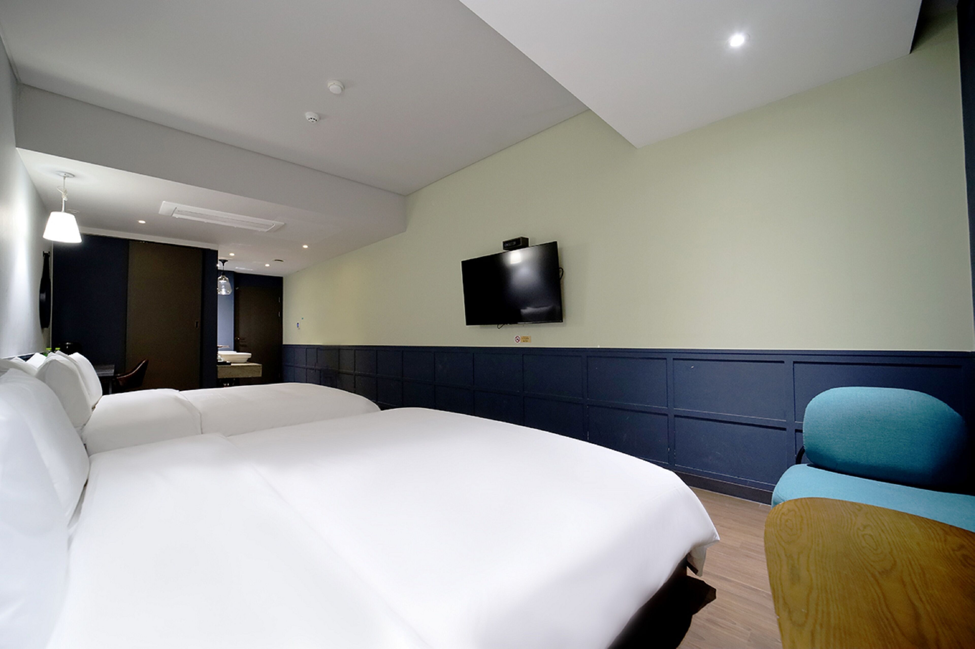 A hotel room with a large bed, a television mounted on the wall, and a wooden chair.