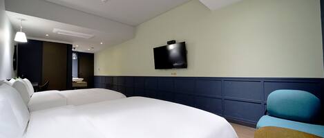 A hotel room with a large bed, a television mounted on the wall, and a wooden chair.