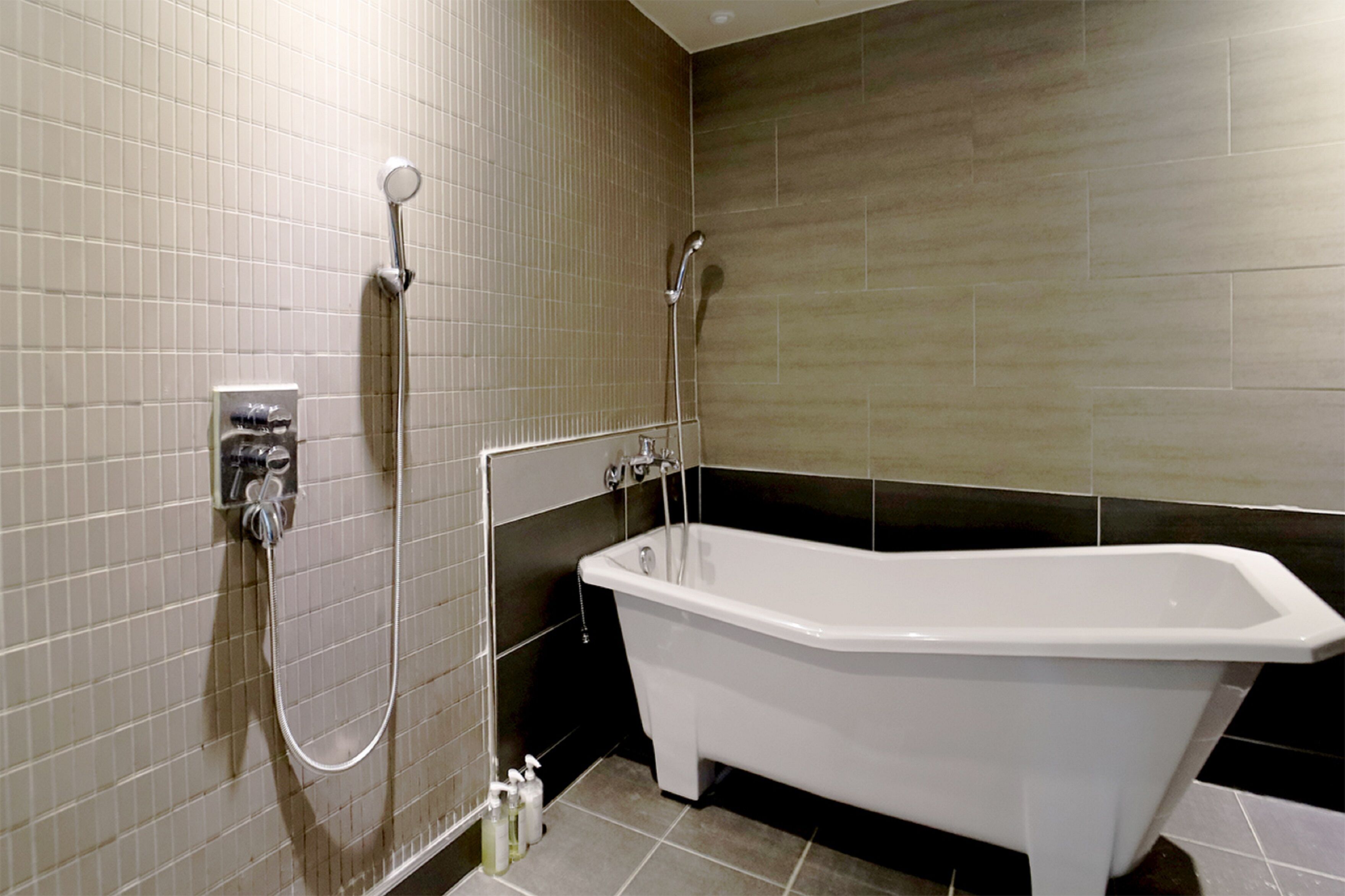 A bathroom with a freestanding bathtub, a showerhead, and a wall-mounted control panel.