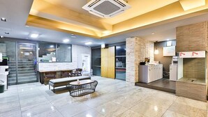 Un vestíbulo moderno con mostrador de recepción, zona de estar y una kitchenette.