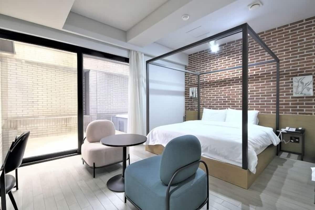 Una habitación de hotel moderna con una cama grande, un balcón, una mesita y dos sillas.