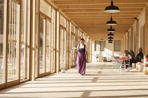 Un vaste espace intérieur doté de grandes fenêtres, de poutres en bois et de luminaires suspendus.