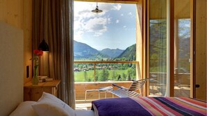 A bedroom with a bed, a nightstand, a vase with flowers, and a view of a balcony with chairs and a table.