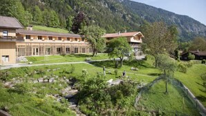 A building with a long, single-story structure, surrounded by a well-maintained grassy area and a mountain backdrop.