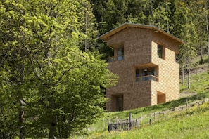 A wooden cabin with a balcony, surrounded by trees.