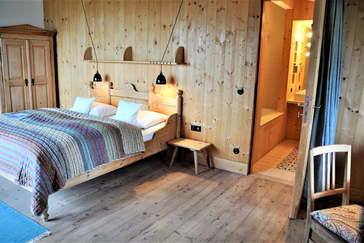A wooden bedroom with a bed, bedside tables, and a wardrobe.