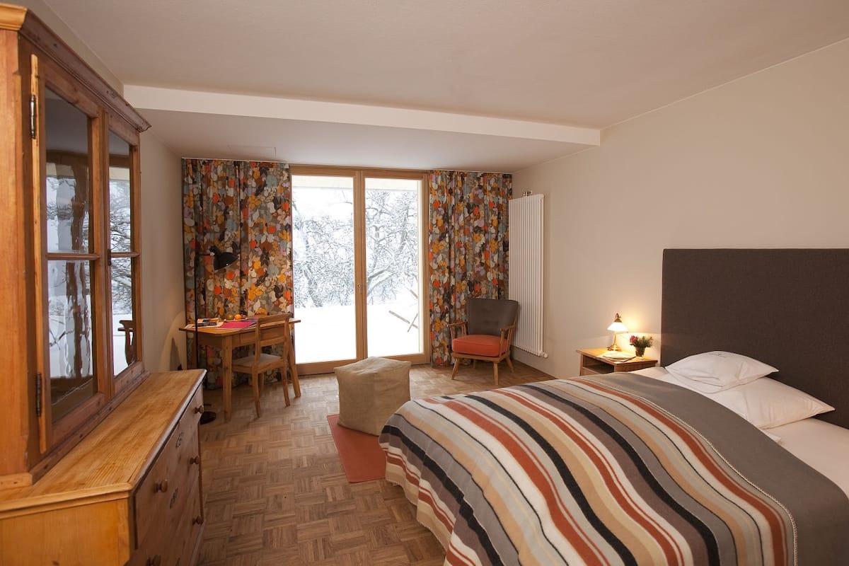 A bedroom with a bed, a desk, a chair, and a radiator.