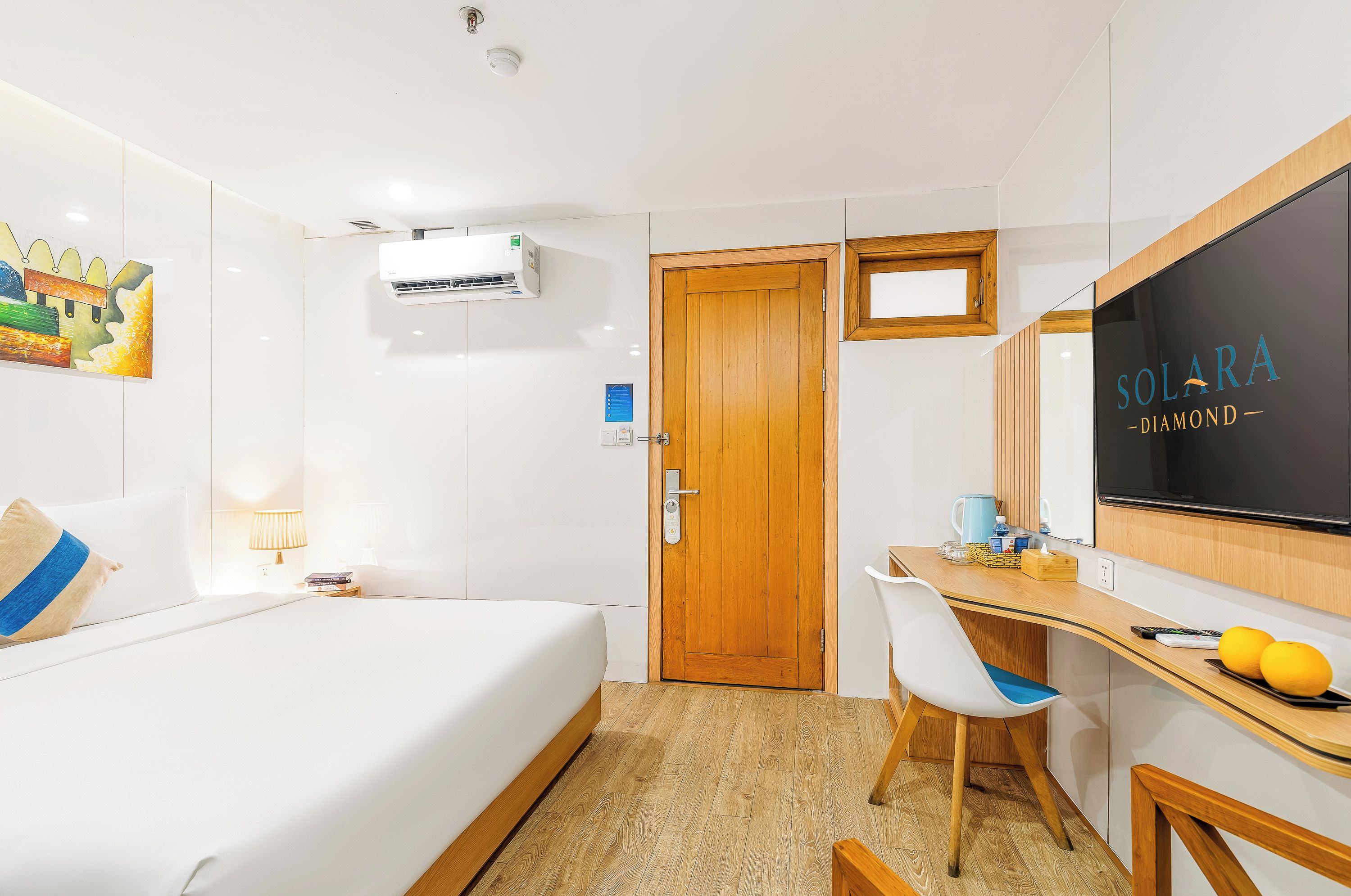 Une chambre d’hôtel avec un lit, un bureau et une chaise, une télévision et une porte.