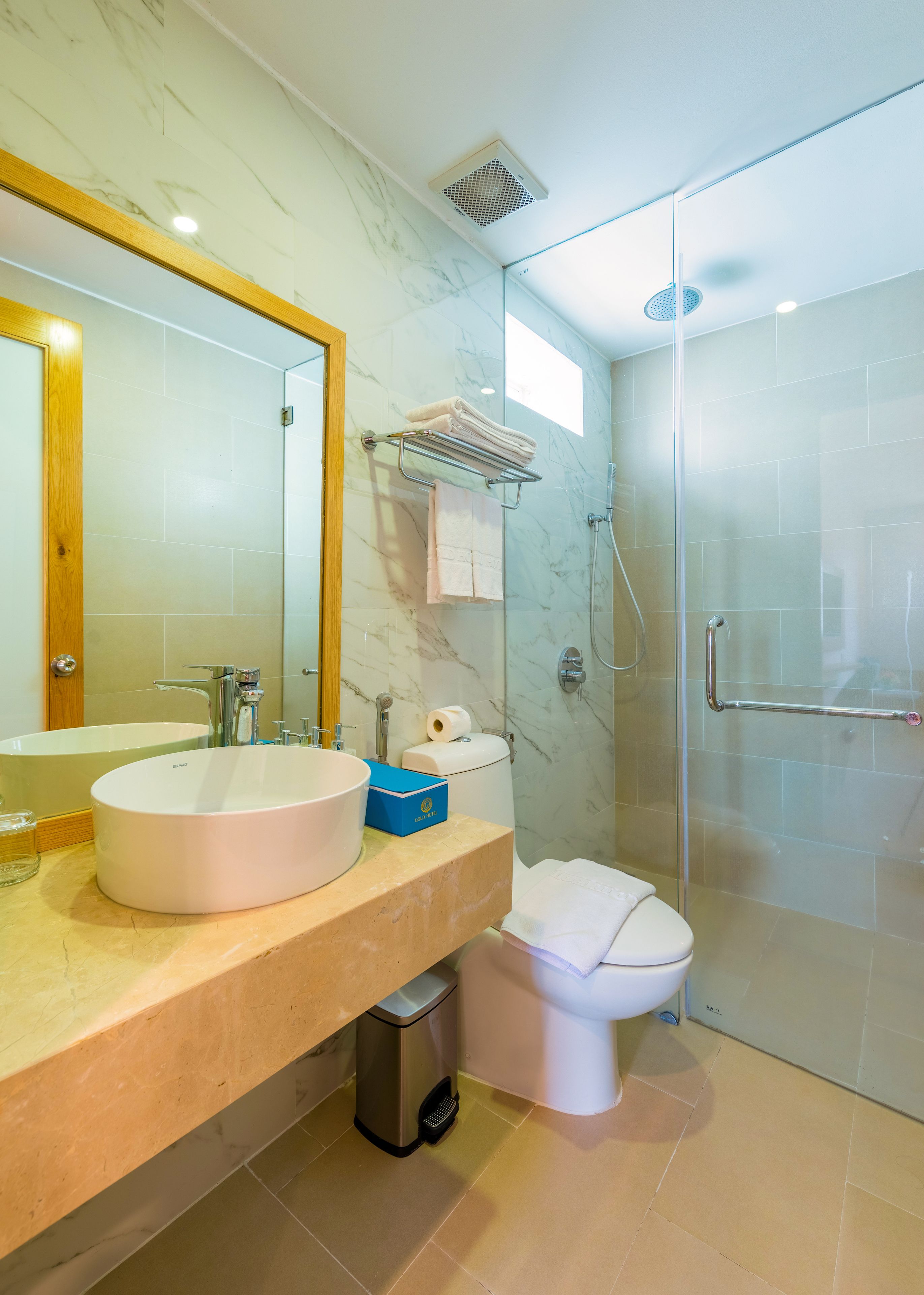 A modern bathroom with a marble vanity, a sink, a toilet, and a glass-enclosed shower.