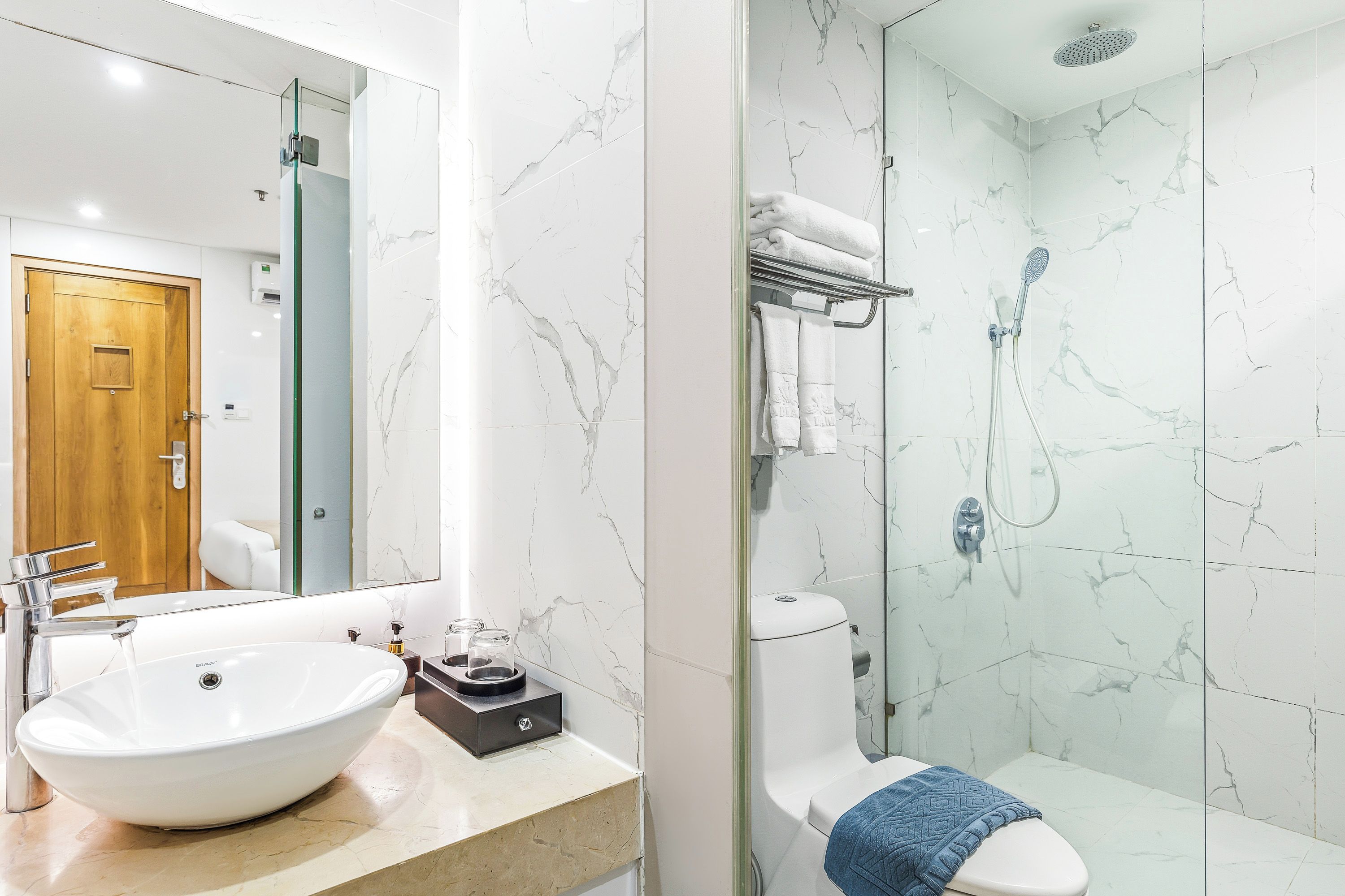 Ein Badezimmer mit einem großen weißen Waschbecken, einem Spiegel, einer Dusche mit Duschbrause und einer Toilette mit Handtuch.