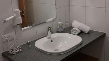 A bathroom with a white sink, a mirror, a towel rack, and a bottle of hand soap.