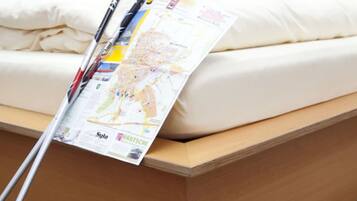 A bed with a map and trekking poles leaning against it.