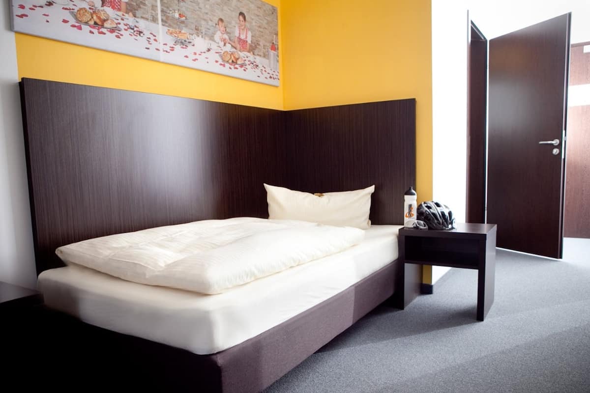 Una habitación de hotel moderna con una cama grande, una mesita de noche y una puerta.