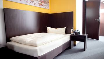 Una habitación de hotel moderna con una cama grande, una mesita de noche y una puerta.