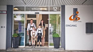 Entrada de un hotel con una familia posando frente a él.