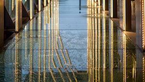 Un pasillo con superficies reflectantes y líneas verticales iluminadas.