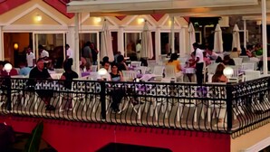 An outdoor dining area with tables and chairs, a railing, and a view of the interior. - Destina Hotel (Fethiye)
