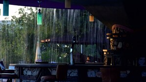 An outdoor bar area with stone walls, hanging lanterns, and a view of trees through a window. - Destina Hotel (Fethiye)