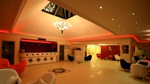 A modern lobby with a high ceiling, a central chandelier, and a reception area with red and white decor. - Destina Hotel (Fethiye)