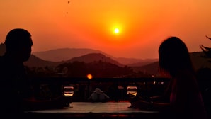 A couple sitting at a table with a view of a sunset over mountains. - Destina Hotel (Fethiye)