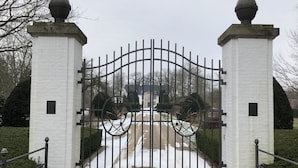 Une entrée fermée par un portail, avec un chemin pavé menant à un bâtiment.