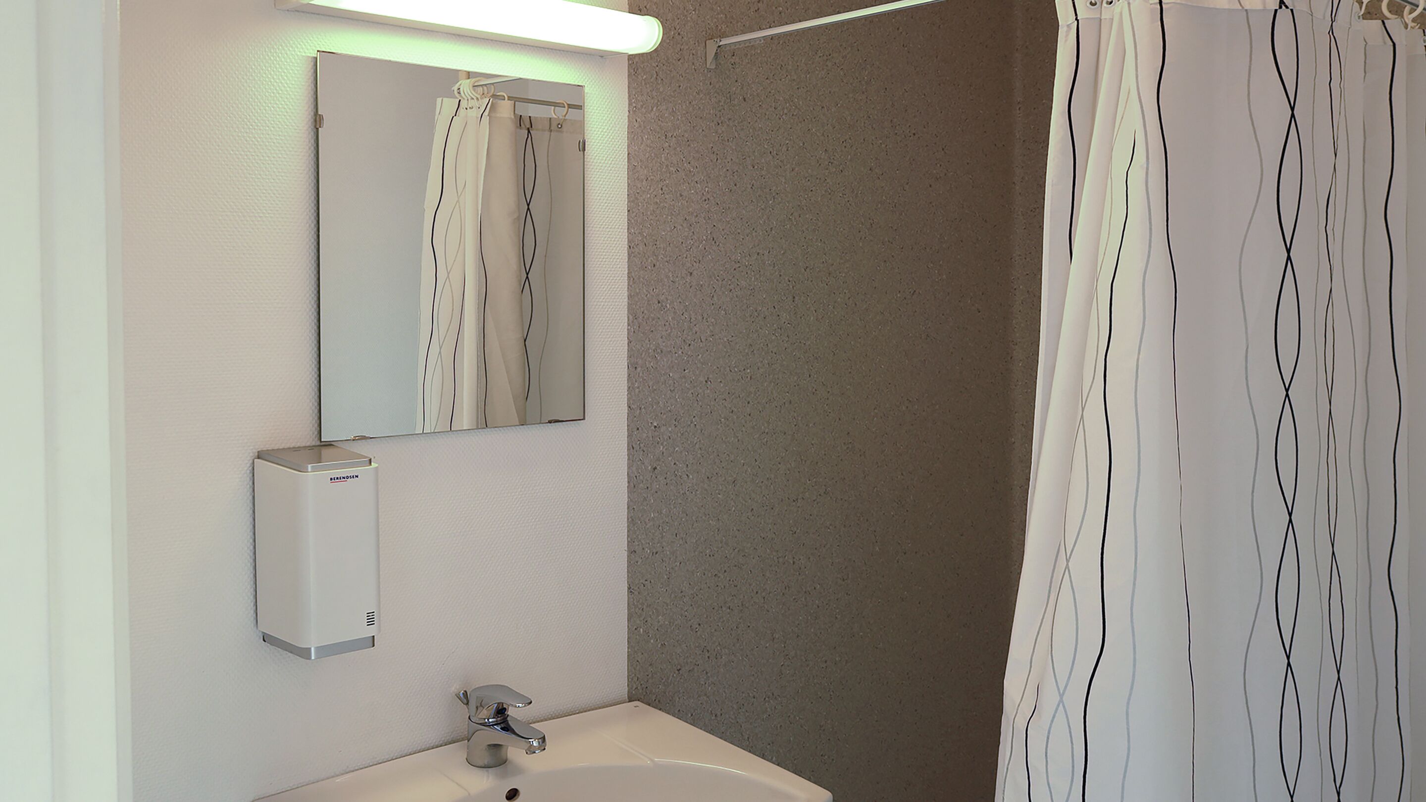 A bathroom with a sink, mirror, and shower curtain.