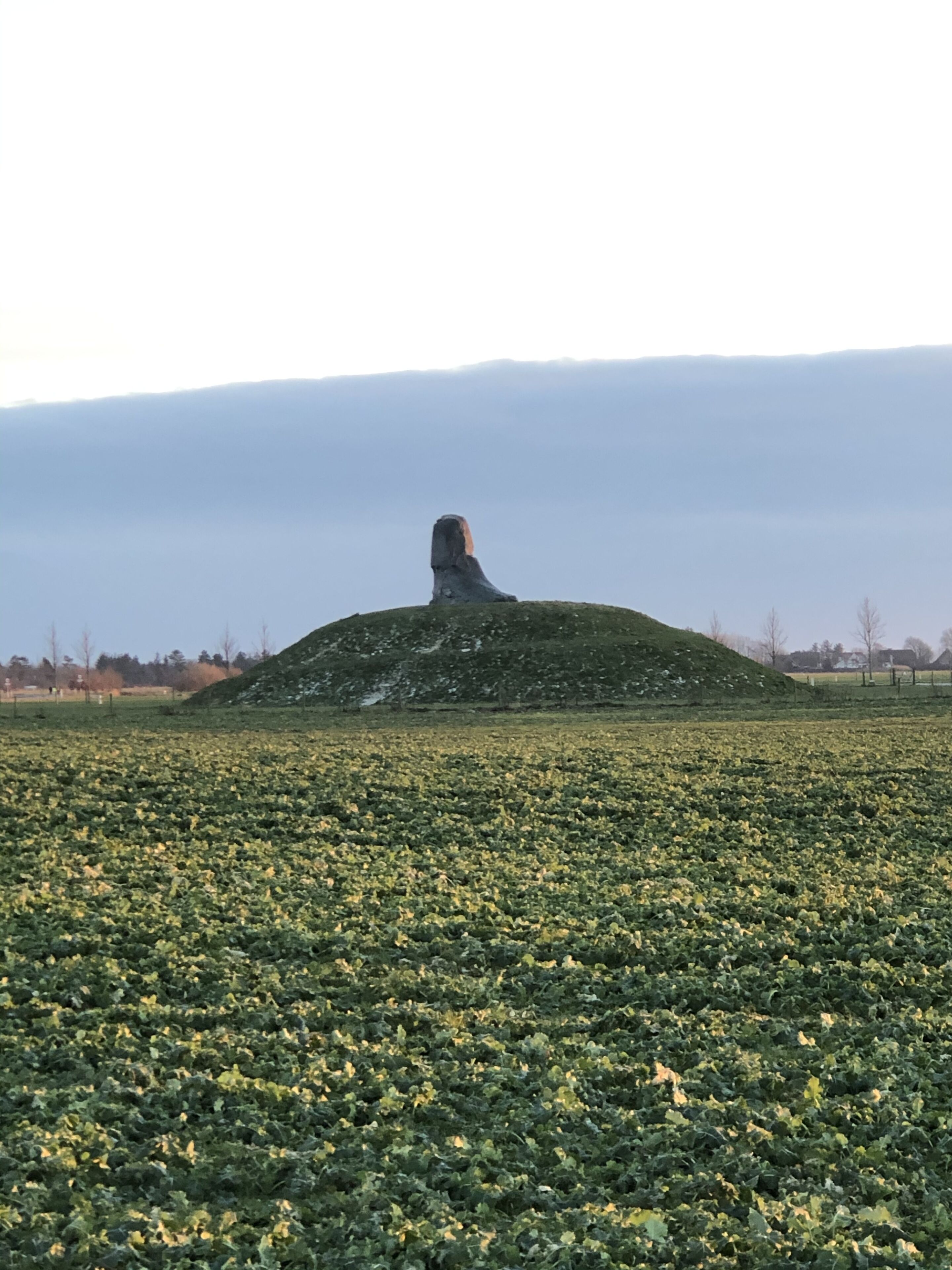 A large, isolated hill with a statue in the center.