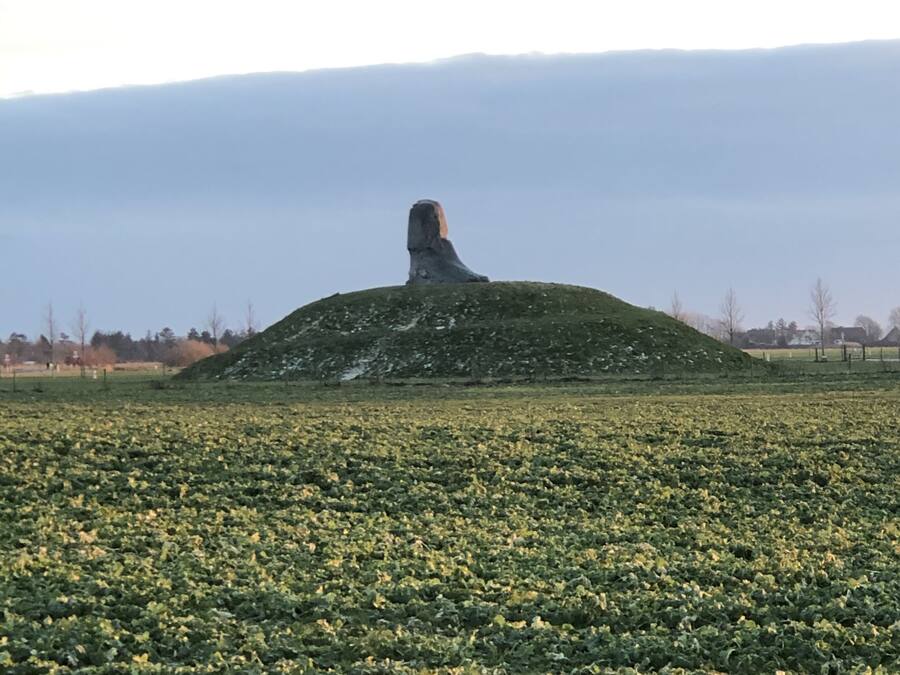 A large, isolated hill with a statue in the center.