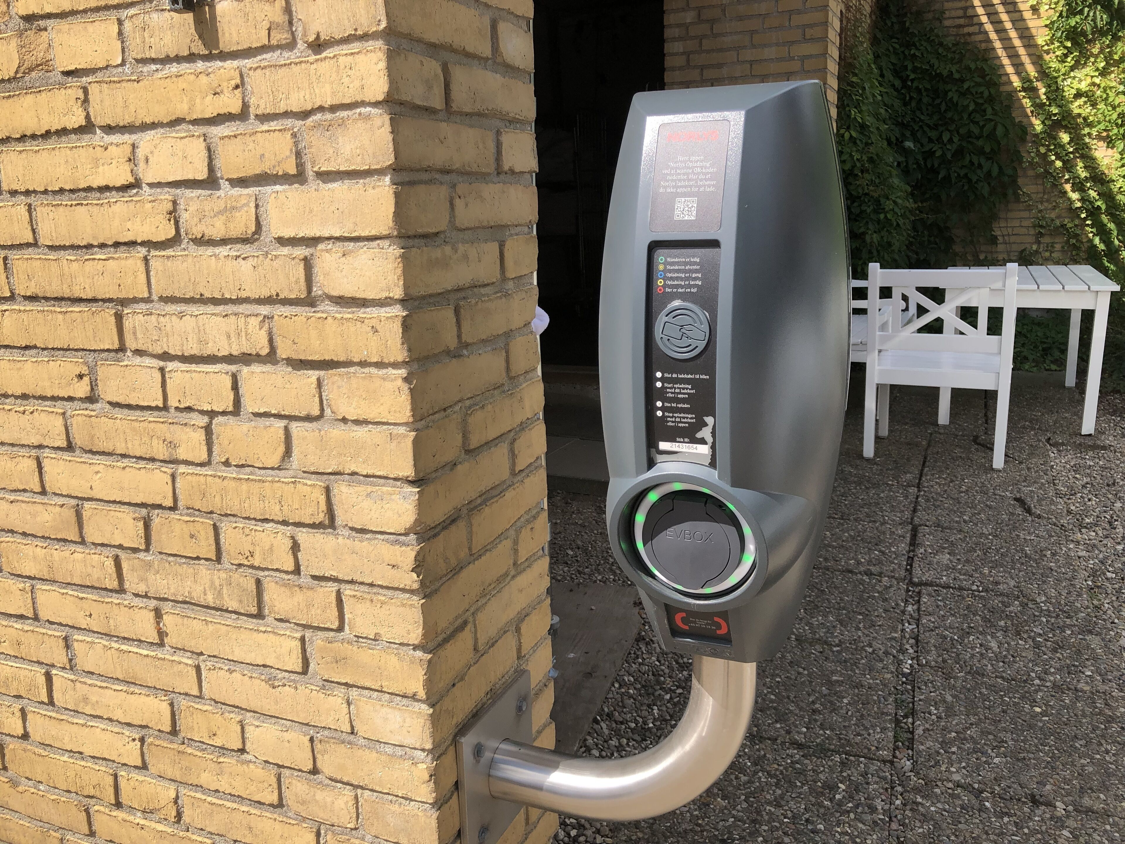 Ein Parkscheinautomat an einer Backsteinmauer, mit einem QR-Code und Anweisungen in verschiedenen Sprachen.