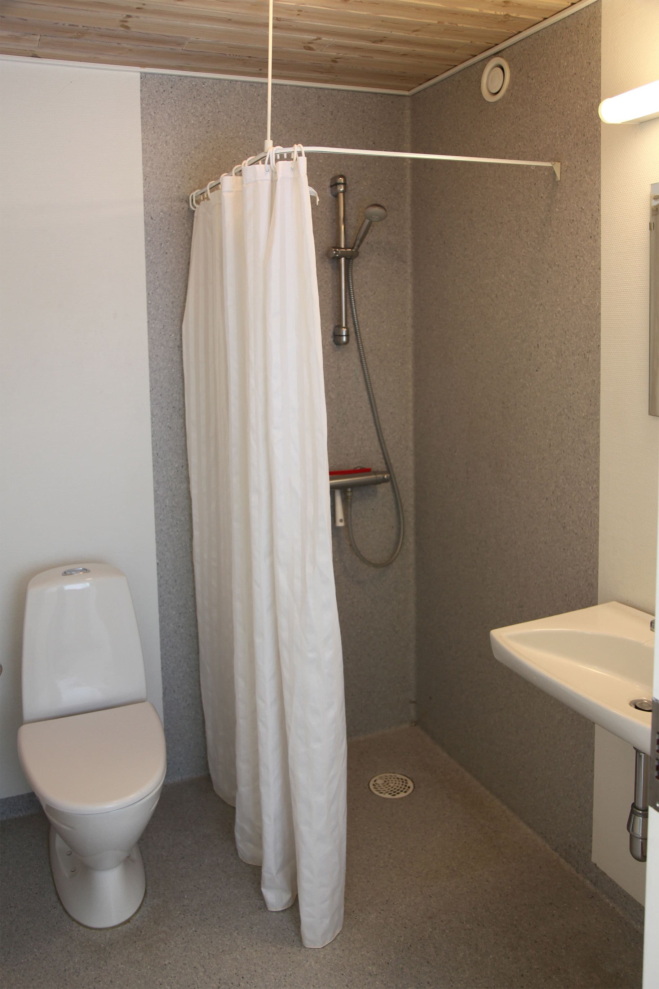 Ein kleines Badezimmer mit Toilette, einer Dusche mit Duschvorhang und einem Waschbecken.