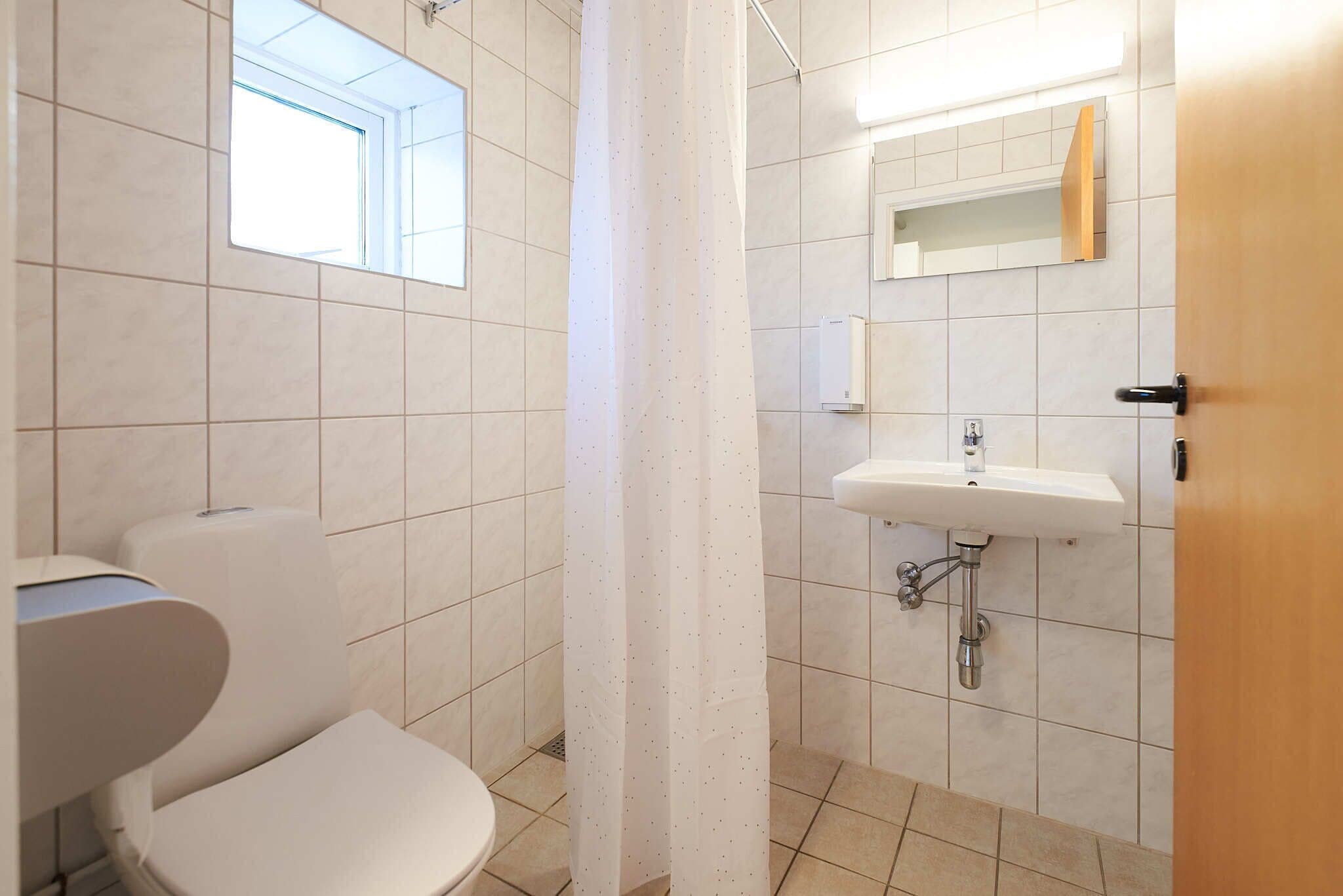 Een badkamer met toilet, wastafel en douchegordijn.